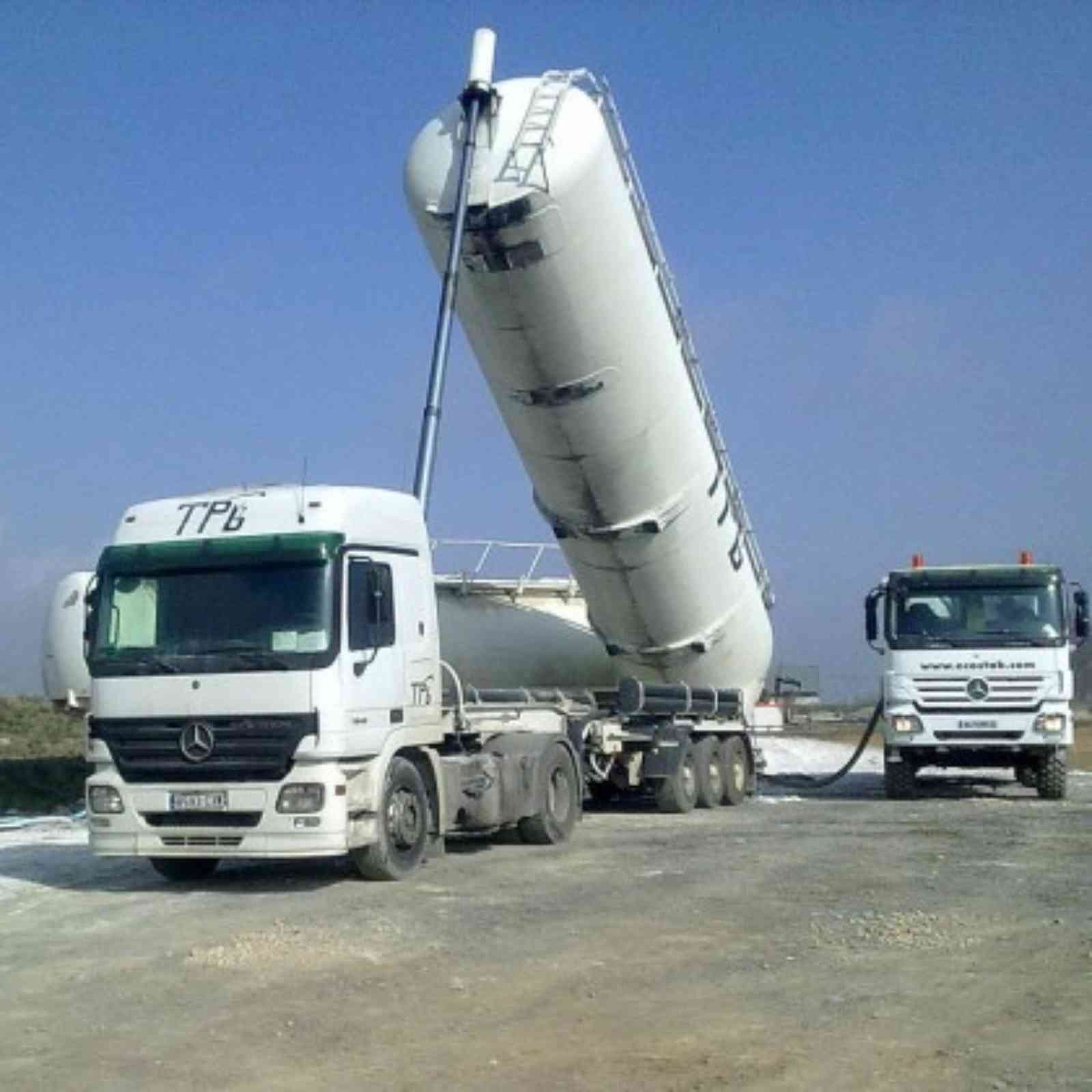 Dos camiones blancos con TPB escrito en el costado