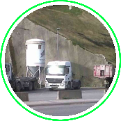 Un camión circula por una carretera al lado de un silo.