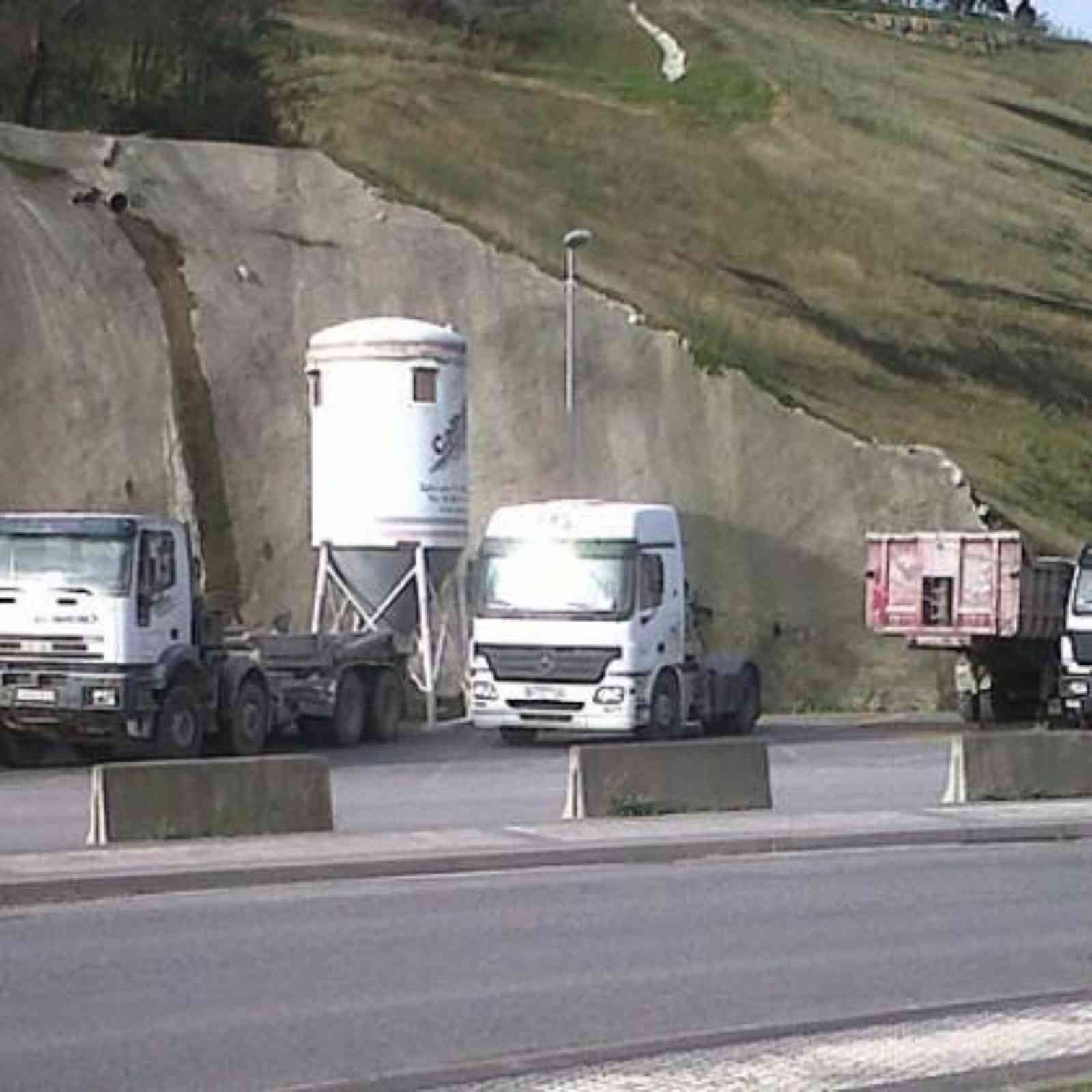 Varios camiones están estacionados al costado de la carretera.
