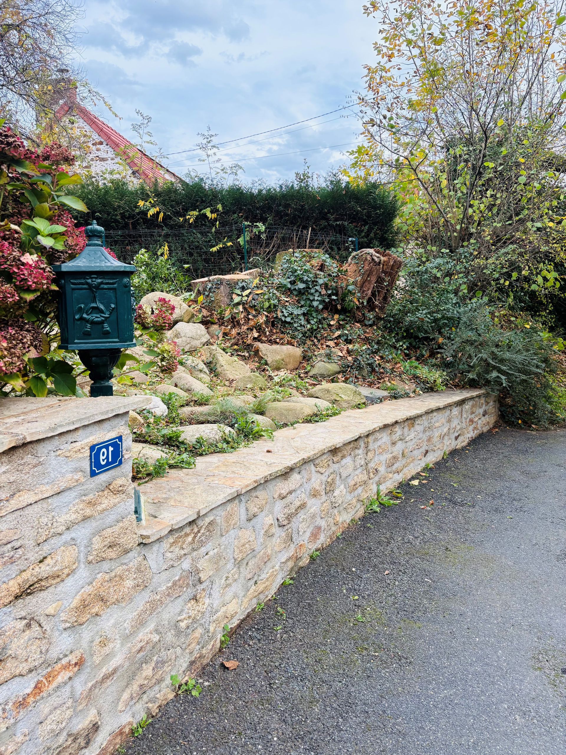 Terrasse avec chaises bleues, foyer et petite table en pierre, donnant sur une cour gazonnée.