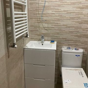 Un baño con lavabo, inodoro y toallero.