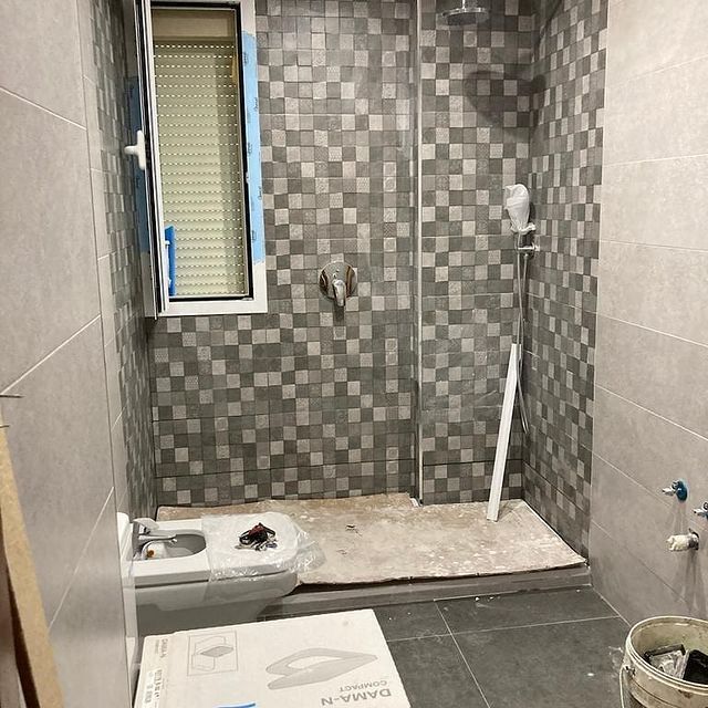 Un baño con inodoro, ducha y ventana.