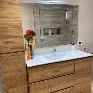 Un baño con lavabo, espejo y muebles de madera.