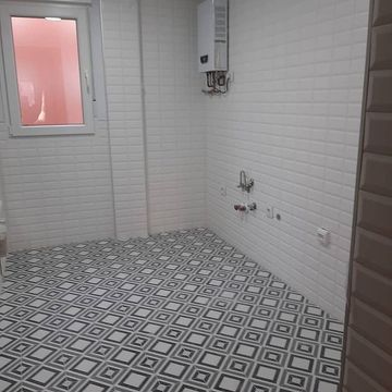 Una cocina con azulejos blancos y suelo de baldosas blancas y negras.