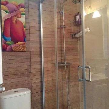 Un baño con inodoro, ducha y un cuadro en la pared.