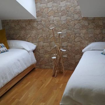 Un dormitorio con dos camas y una pared de piedra.