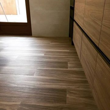Una cocina con piso de madera y gabinetes.