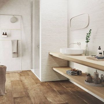 Un baño con lavabo, espejo y suelo de madera.