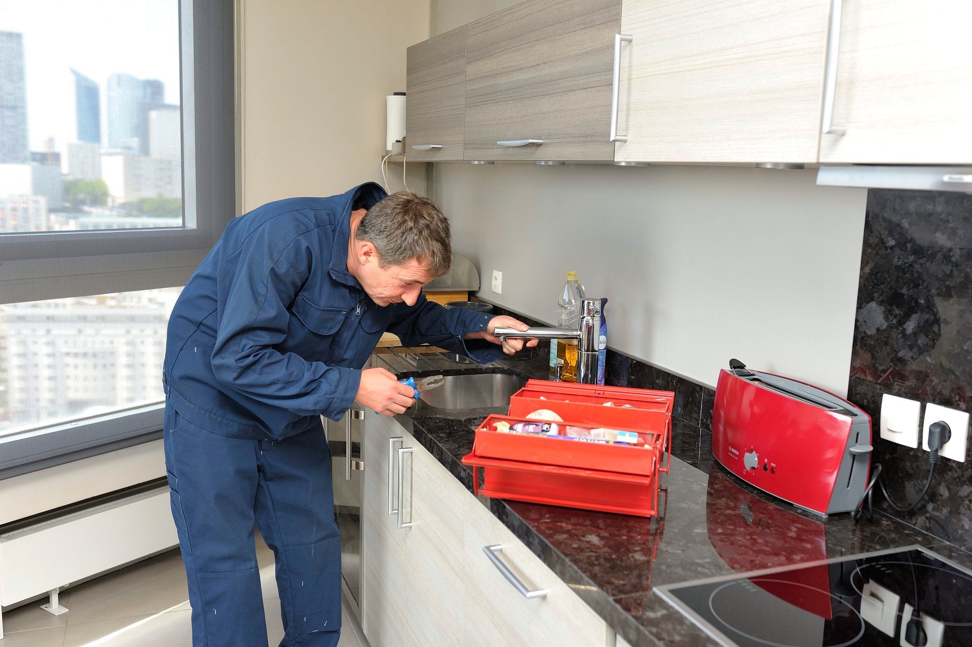 Dans un appartement moderne et lumineux, une personne inspecte un robinet de cuisine.