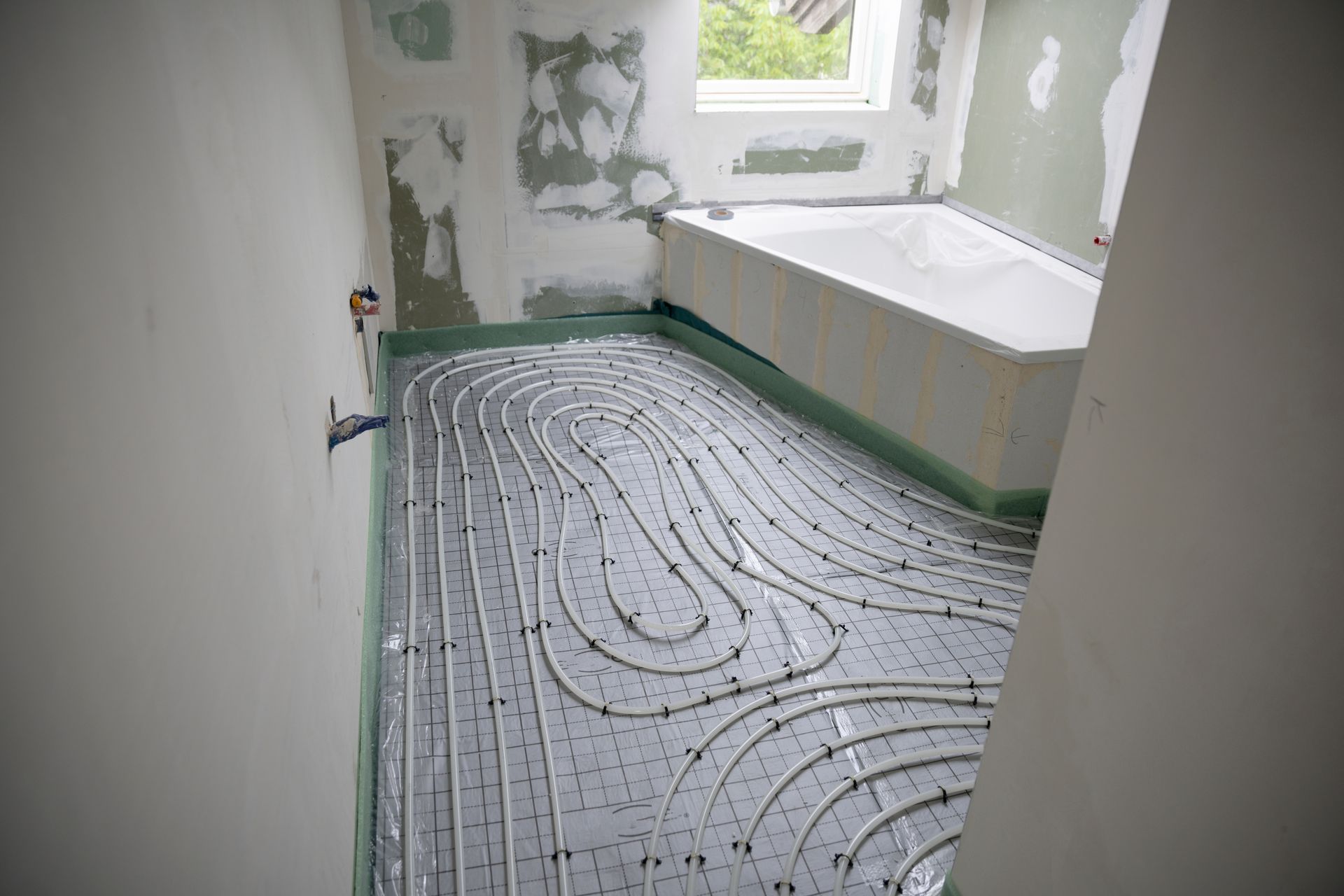 Une salle de bains en cours de rénovation avec des tuyaux de chauffage au sol.