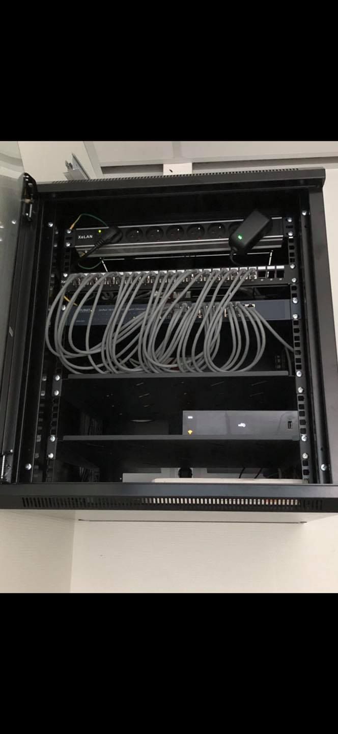 Un rack réseau noir avec des câbles et des périphériques montés à l'intérieur.