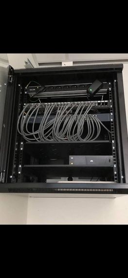 Un rack réseau noir avec des câbles et des périphériques montés à l'intérieur.
