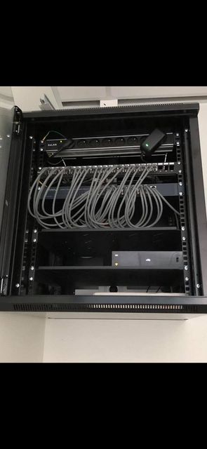 Un rack réseau noir avec des câbles et des périphériques montés à l'intérieur.