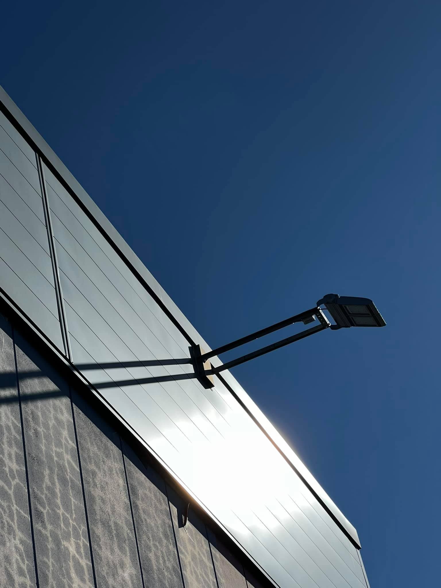Des panneaux solaires sur un bâtiment reflètent la lumière du soleil, avec une lampe noire s'étendant sur une journée