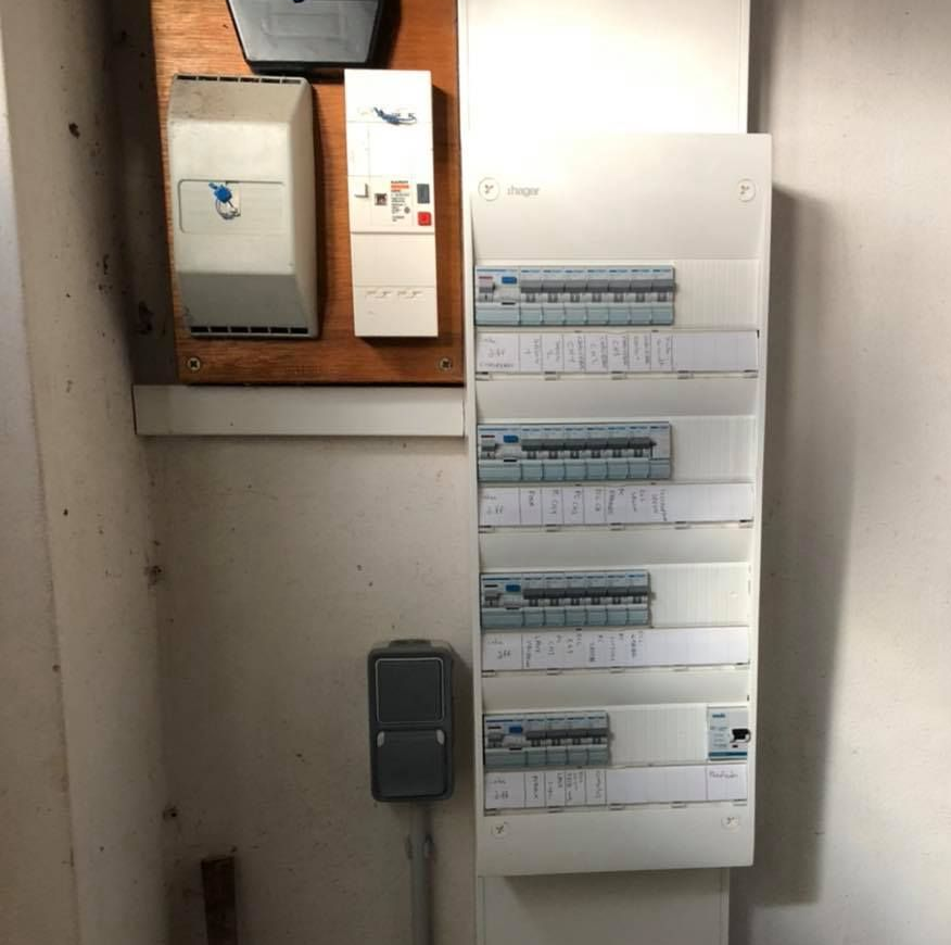 Panneau électrique avec disjoncteurs, interrupteurs et compteurs montés sur un mur.