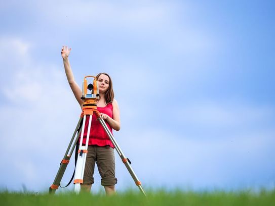 Frau mit Vermessungsgerät hebt ihren Arm