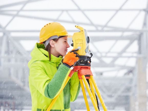 Bauarbeiter schaut durch Vermessungsgerät