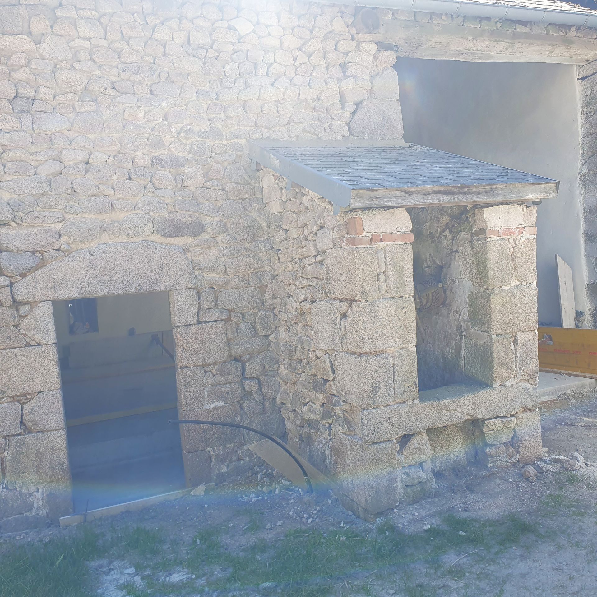 Façade en pierre d'un bâtiment avec porte ouverte et petit porche