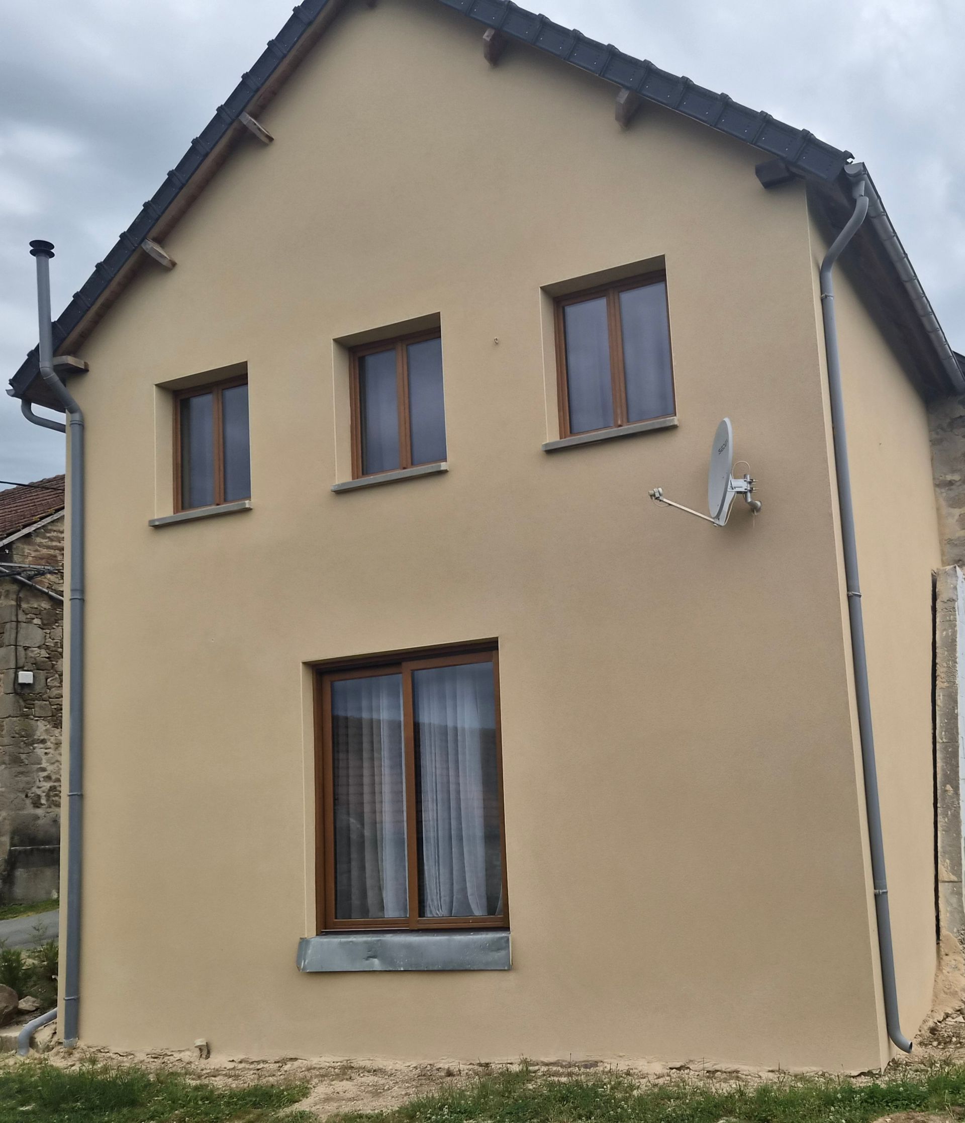 Rénovation de façade maison beige à deux étages avec des fenêtres