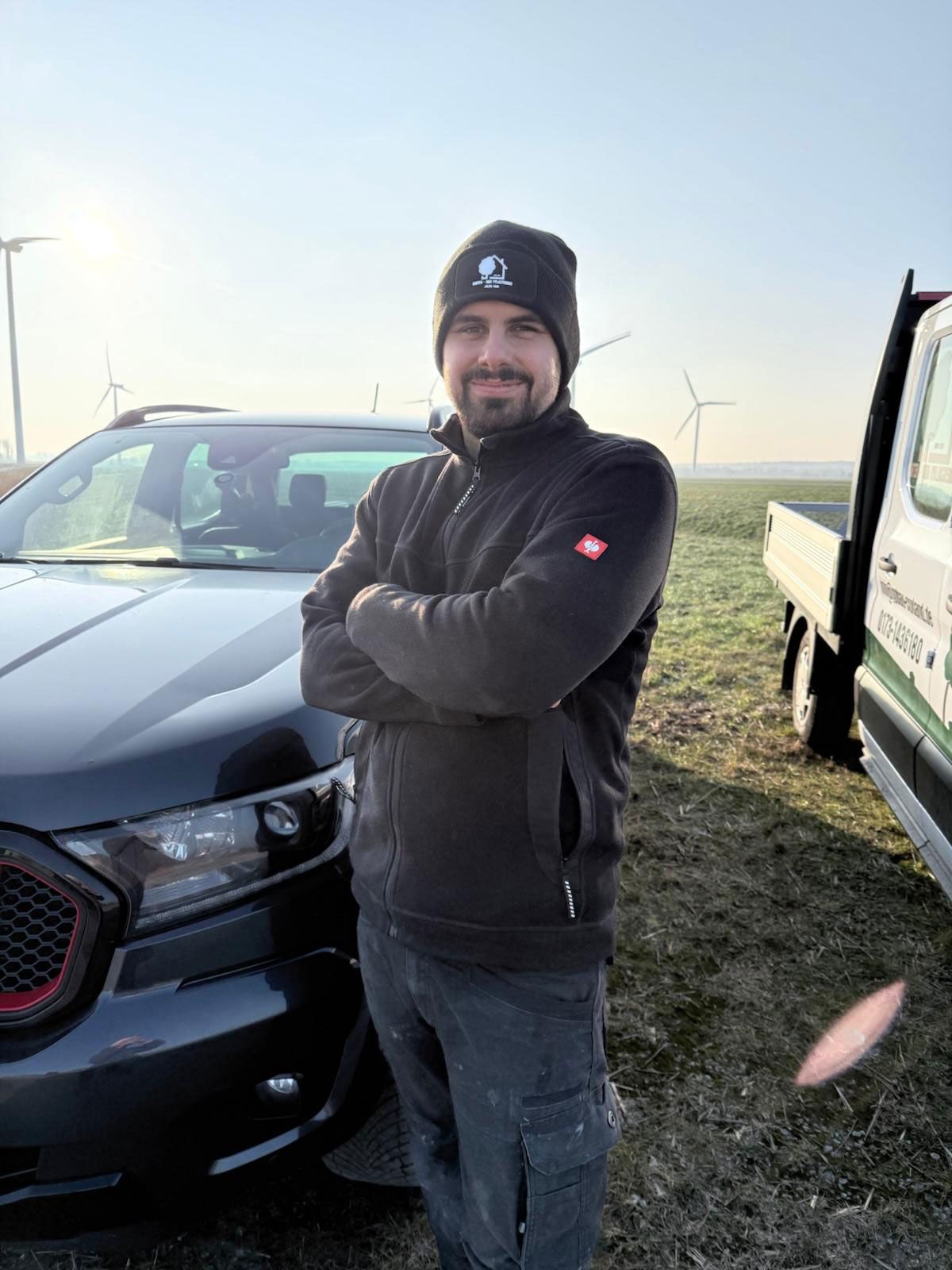 Ein Mann steht neben einem Anhänger und einem LKW.