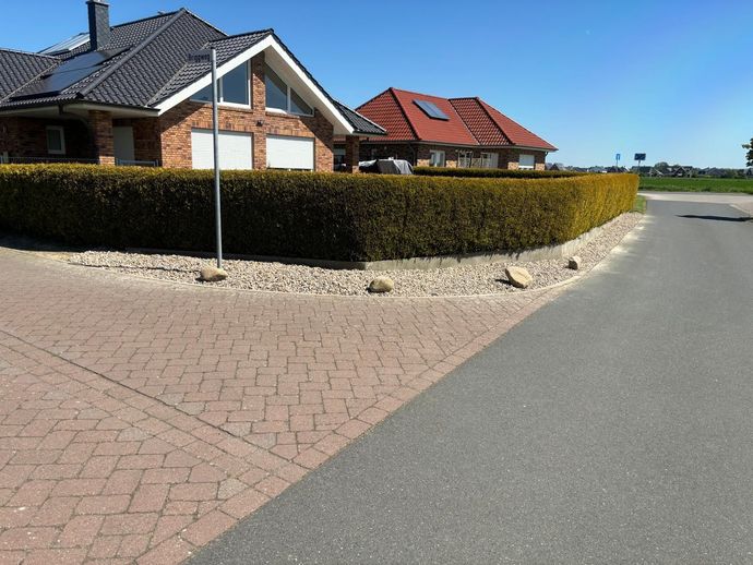 Eine gemauerte Auffahrt, die zu einem Haus mit rotem Dach führt