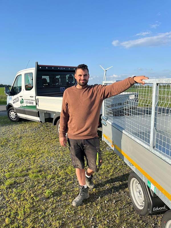 Ein Mann steht neben einem Anhänger und einem LKW.