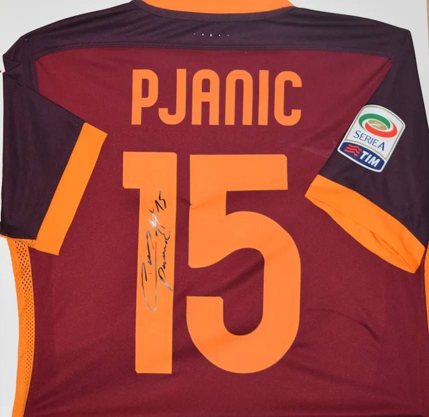 Au dos d'un maillot de football bordeaux de l'AS Roma, floqué « PJANIC 15 » et portant le logo de la Serie A. Il est signé.