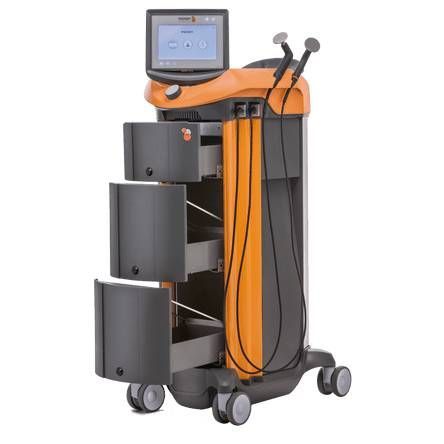 Dispositif médical orange et gris avec écran tactile, tiroirs et baguettes thérapeutiques portables.