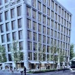 Immeuble de bureaux moderne à plusieurs étages, avec de nombreuses fenêtres et des passants sur le trottoir.