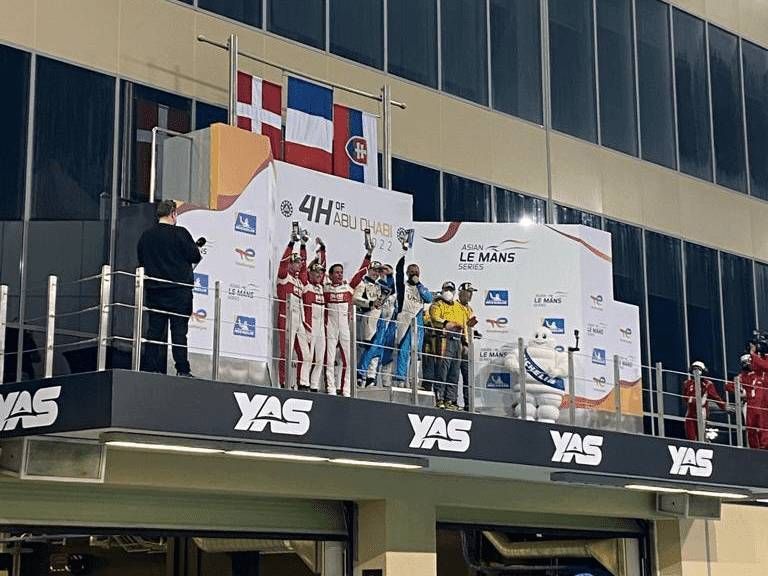 Podium des vainqueurs, trophées levés, sur le circuit de Yas Marina. Les drapeaux du Danemark, de la Slovaquie et de la France flottent au vent.