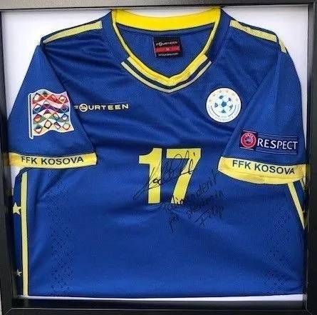Maillot de football bleu et jaune du Kosovo avec le numéro 17 et des autographes, encadré.