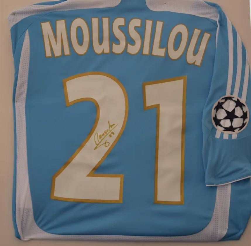 Maillot de football bleu clair avec l'inscription « MOUSSILOU 21 » et une signature.