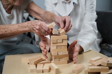 Dos personas mayores están jugando un juego con bloques de madera.