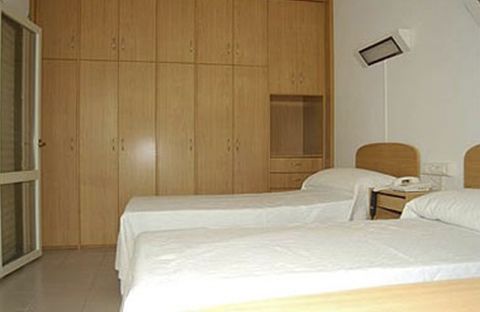 Un dormitorio con dos camas, una mesita de noche y un armario.