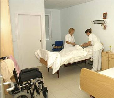 Dos enfermeras están trabajando con un paciente en una habitación de hospital.