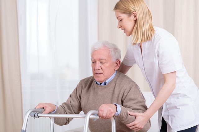 Una enfermera está ayudando a un anciano a usar un andador.