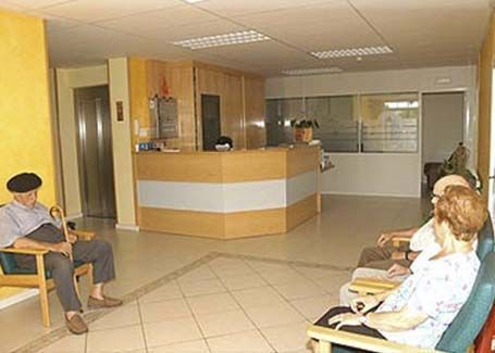 Un grupo de personas están sentadas en sillas en una sala de espera.