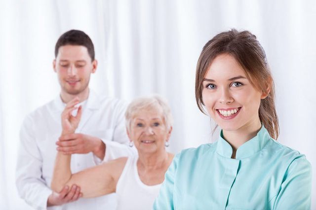 Una mujer está parada frente a dos médicos y sonriendo.