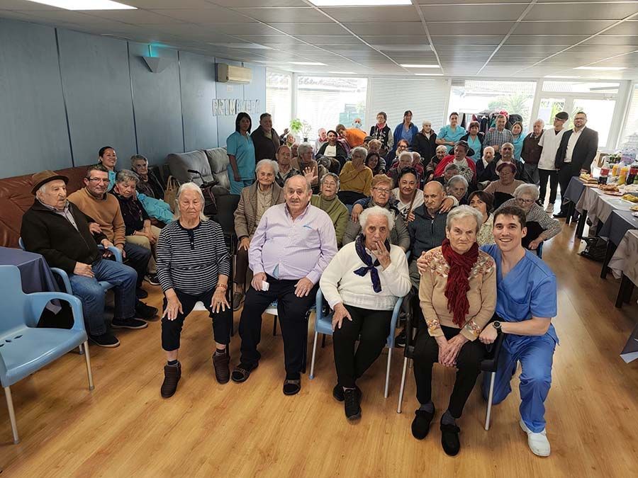 Grupo de personas sentadas en una habitación luminosa, mirando a la cámara durante una reunión.