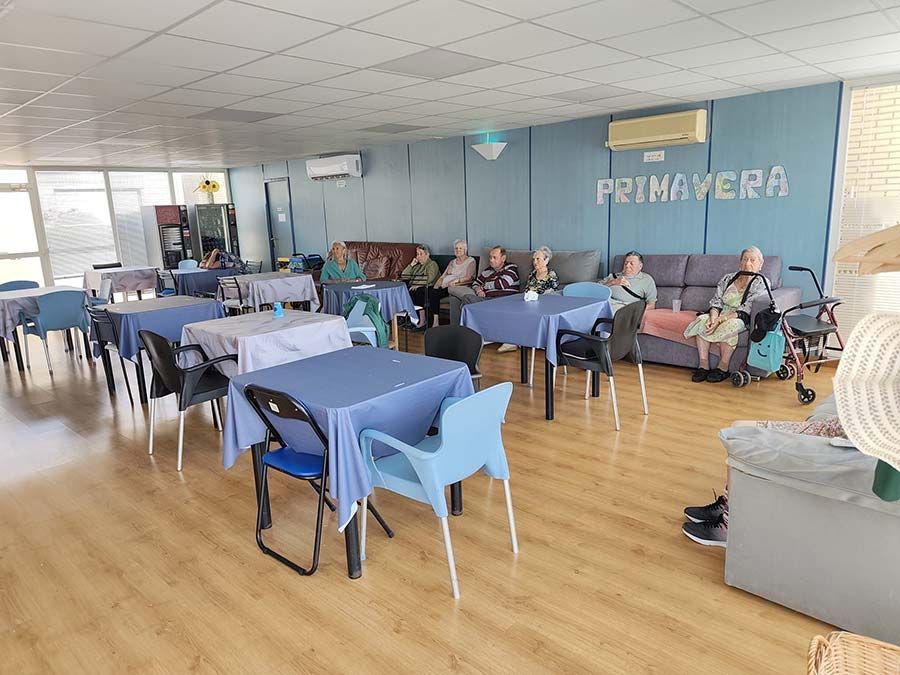 La gente estaba sentada en una luminosa sala comunitaria con manteles azules y un mural que decía 