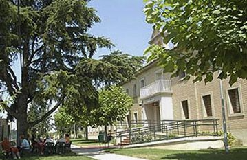 Un grupo de personas está sentada bajo un árbol frente a un edificio.