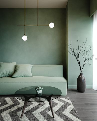 Sala de estar moderna y minimalista con sofá color salvia, lámparas colgantes, alfombra estampada y jarrón con ramas.