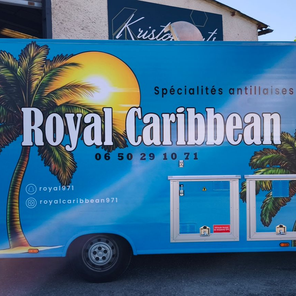 Un food truck bleu orné de palmiers, avec l'inscription Spécialités antillaises et un logo partiel de style caribéen.