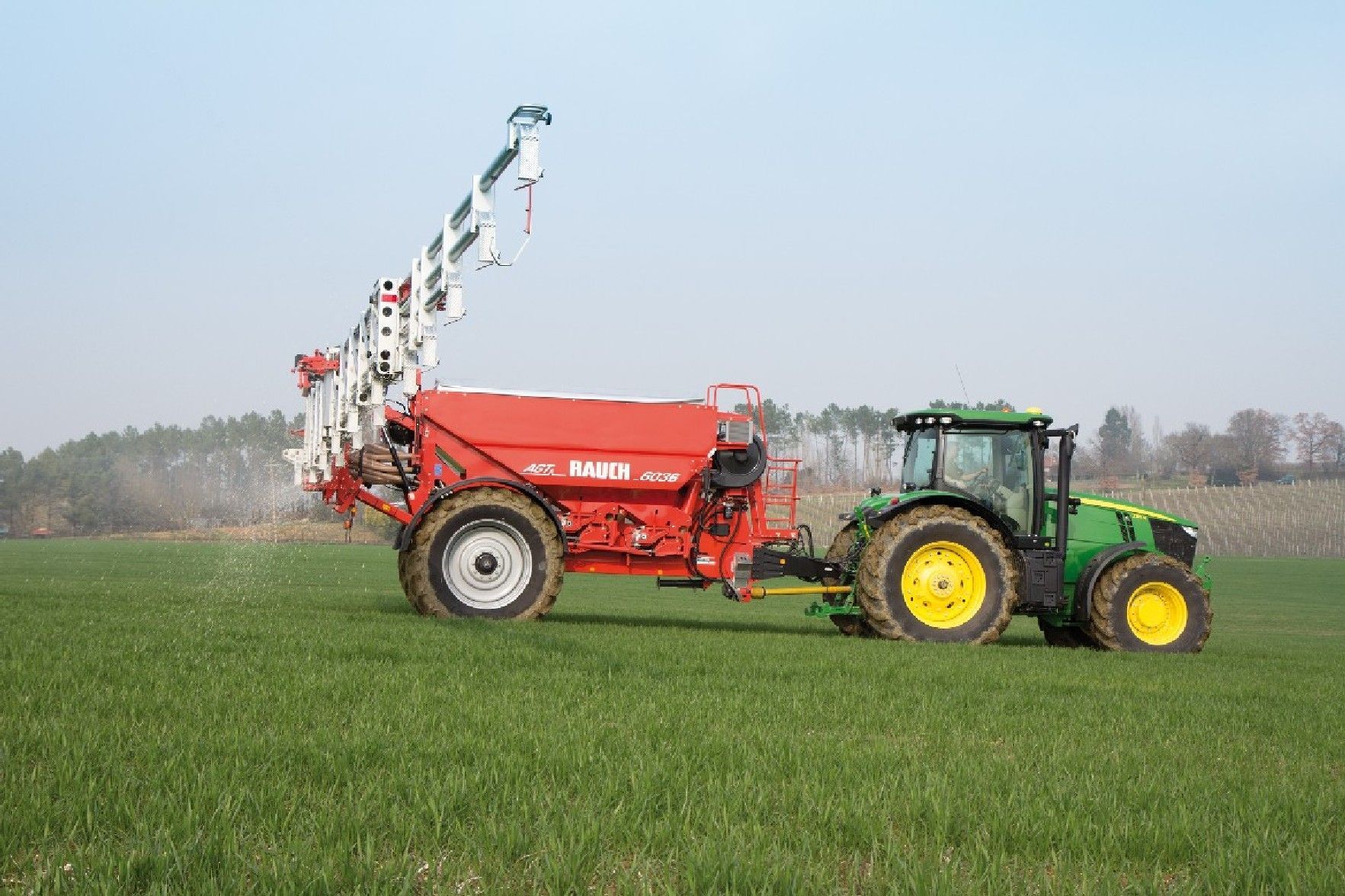 Ein Traktor von John Deere fährt durch ein Grasfeld.