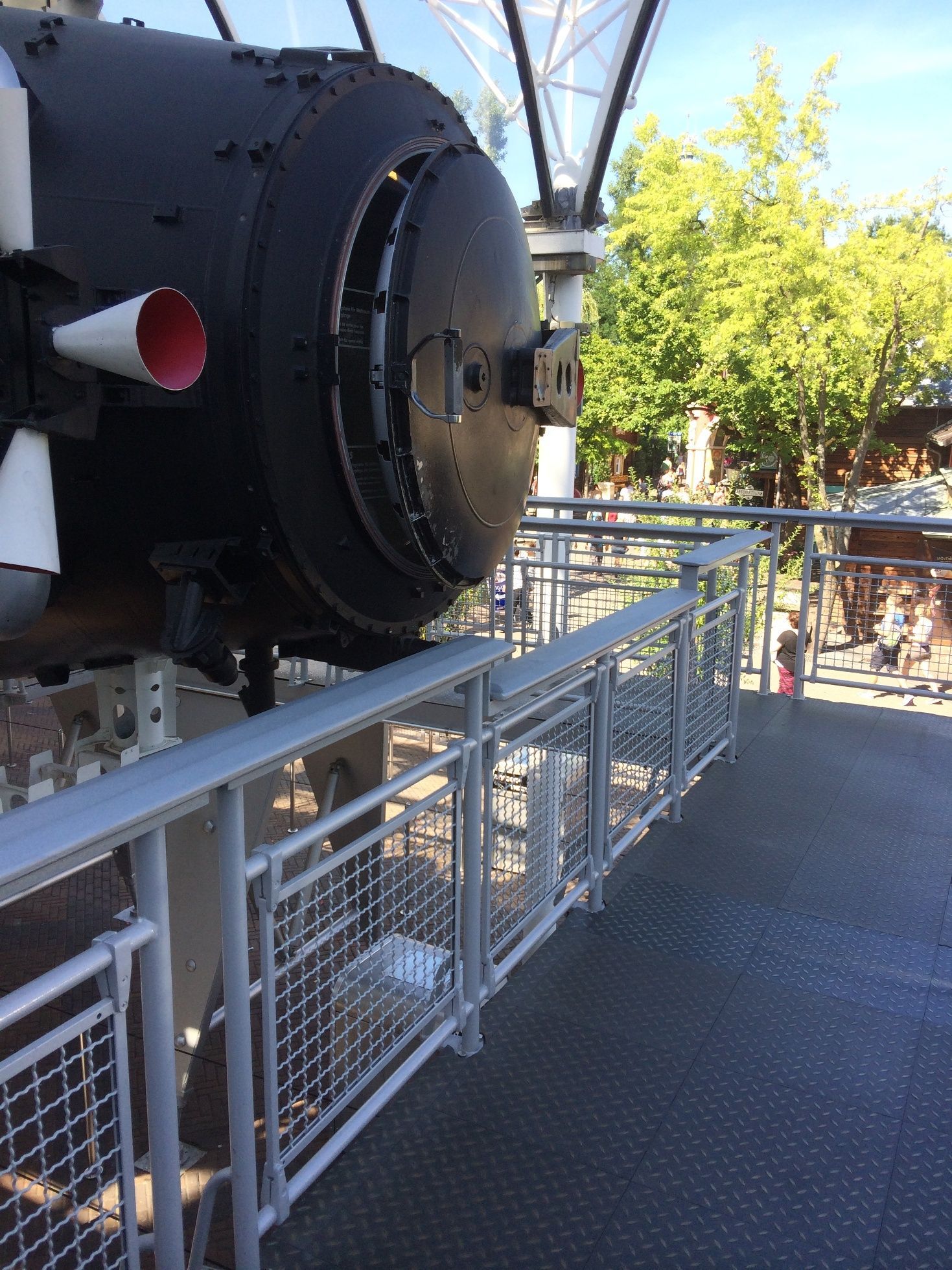 Hinter einem Zaun befindet sich ein großes schwarzes Objekt mit einer roten Spitze.