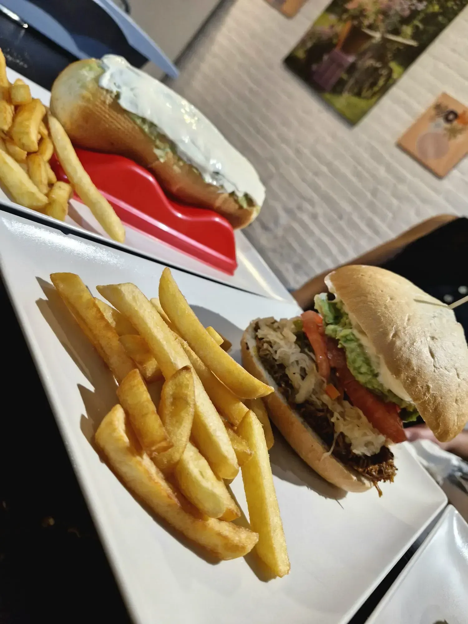 Hamburguesas y patatas fritas servidas en un plato sobre una mesa en un ambiente de restaurante informal.