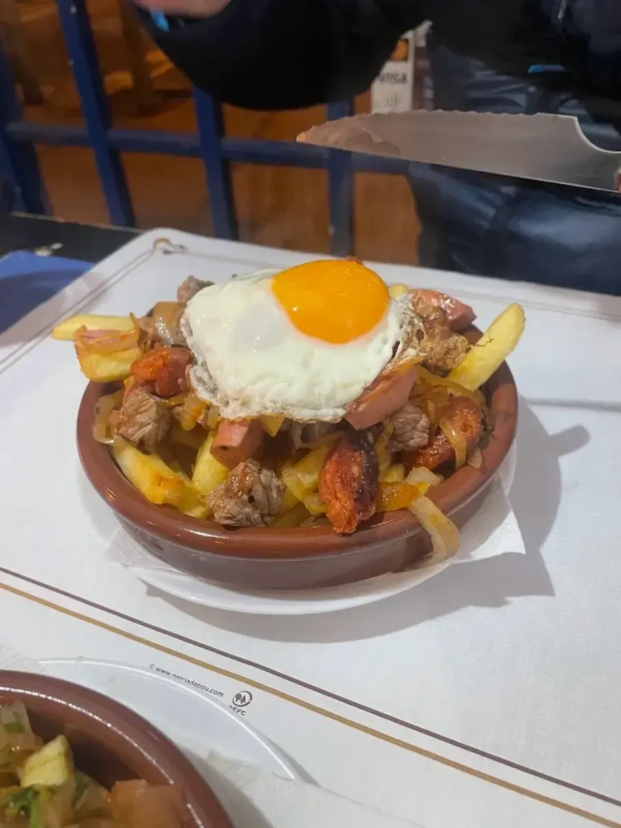 Plato de nachos coronado con un huevo frito sobre la mesa de un restaurante.