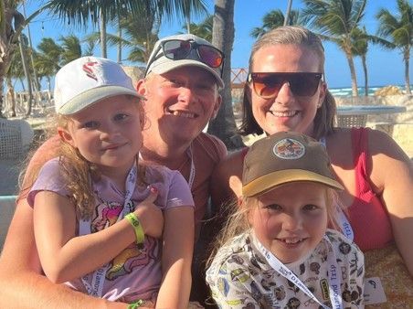 eine Familie posiert für ein Foto am Strand .