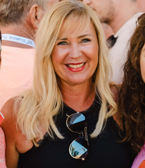 eine blonde Frau lächelt und trägt eine Sonnenbrille