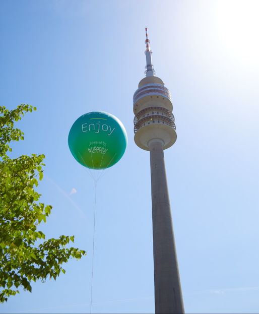 ein grüner Ballon mit der Aufschrift enjoy hängt neben einem Turm